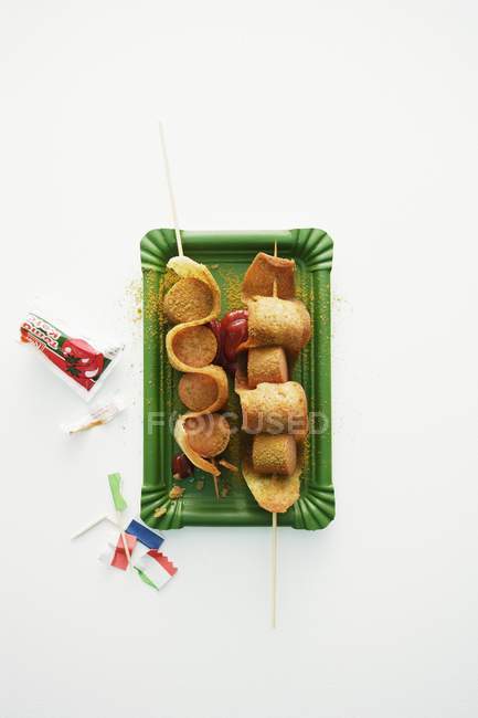 Vista dall'alto delle salsicce al curry La ola su spiedini su piatto di carta verde e fondo bianco — Foto stock