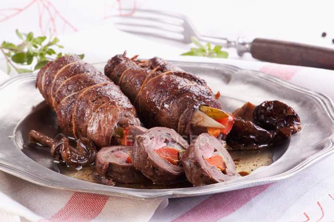Goose roulade stuffed with peppers, gherkins and mushrooms on platter over cloth — Stock Photo