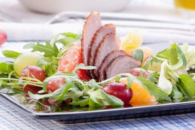 Closeup view of goose breast with oranges, grapes, grapefruit and rocket — Stock Photo