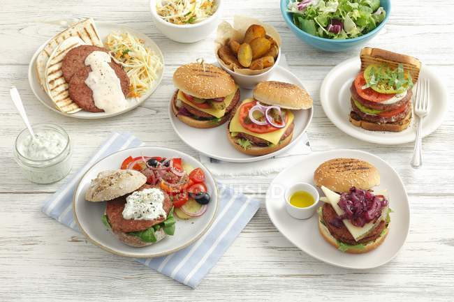 Hambúrgueres variados em pratos — Fotografia de Stock
