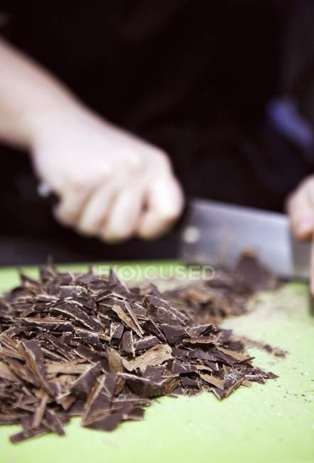 Mani che tagliano cioccolato — Foto stock