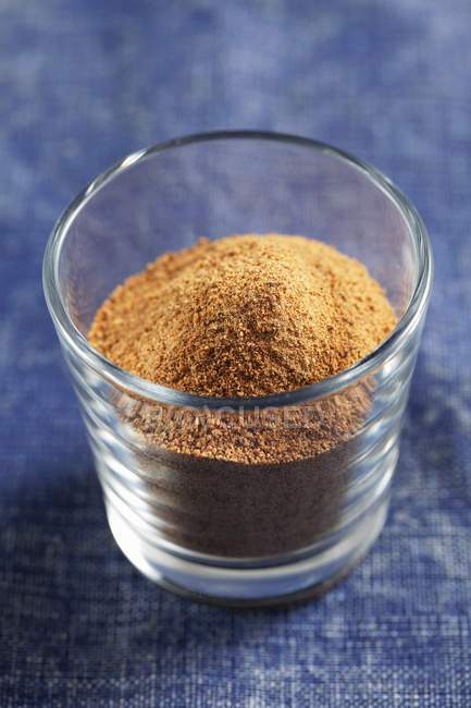 Closeup view of ground nutmeg in a glass on denim — Stock Photo