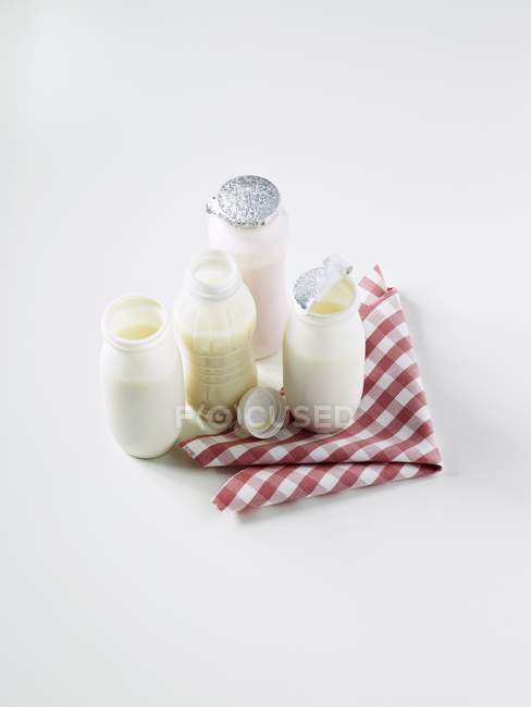 Vista elevada de varias bebidas de yogur en una servilleta a cuadros - foto de stock