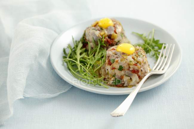 Sarro de arenque con tomates secos, pepinillos en escabeche y huevos de codorniz en plato blanco con tenedor - foto de stock
