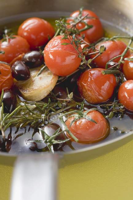 Смажені вишневі помідори з часником та оливками на сковороді — стокове фото