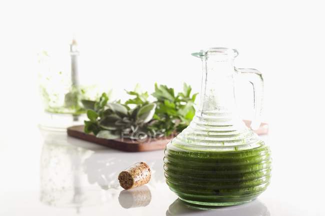 Closeup view of oil with herbs in a jug — Stock Photo