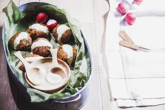 Vegetable fritters with tahini and radishes in dish — Stock Photo