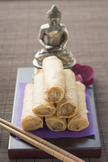 Closeup view of spring rolls in front of Buddha statue — Stock Photo