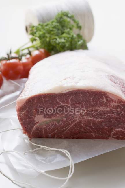 Fresh beef on paper with kitchen string — Stock Photo