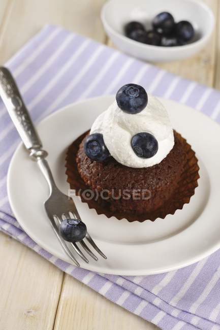 Chocolate muffin topped with cream — Stock Photo