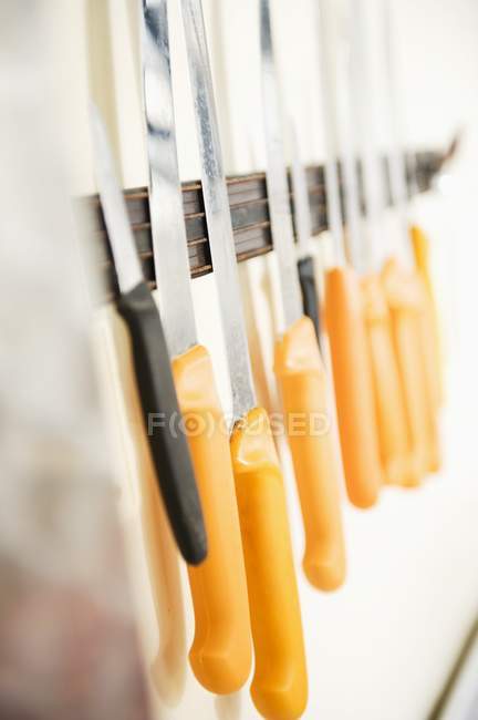 Vista de cerca de varios cuchillos en la banda magnética en una pared - foto de stock