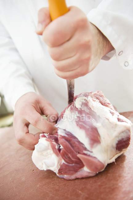 Butcher cutting piece of lamb — Stock Photo