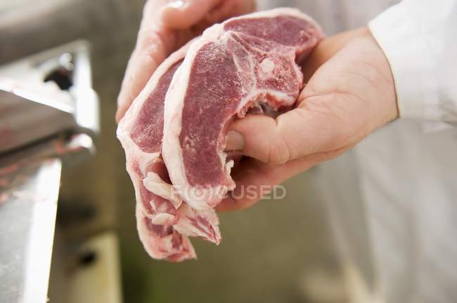 Butcher holding lamb chops — Stock Photo