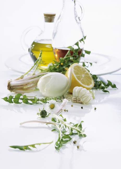 Ingredients for dandelion salad with vinaigrette over white surface — Stock Photo