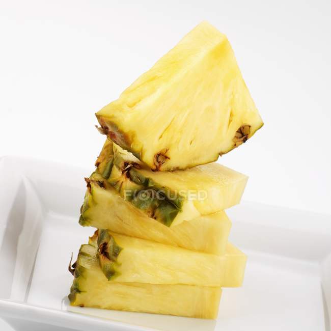 Quartos de abacaxi empilhados em prato branco — Fotografia de Stock