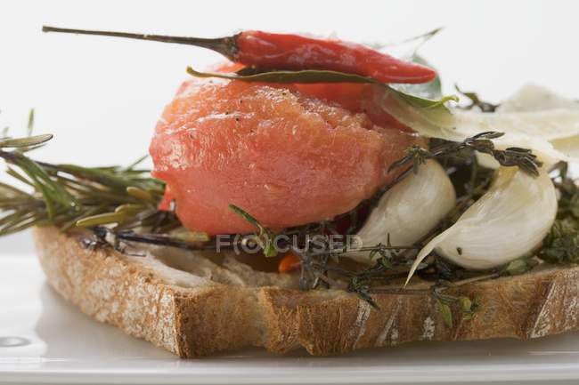 Tomato, chilli, garlic and herbs on bread  on white plate — Stock Photo