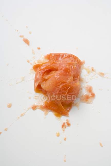 Burst cooked tomato on white surface — Stock Photo