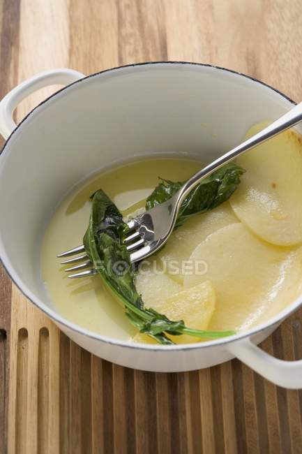 Braised kohlrabi in a pan with fork over wooden surface — Stock Photo