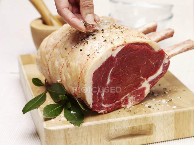Female hand flavouring raw beef — Stock Photo