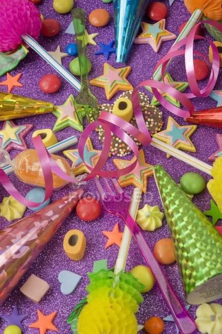 Vista de cerca de varias decoraciones de fiesta con poppers de fiesta, dulces y pajitas - foto de stock