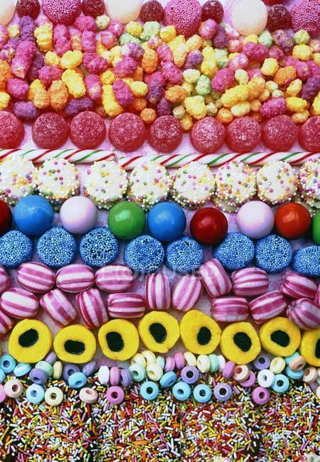 Vista superior de filas dispuestas de dulces y caramelos de colores - foto de stock