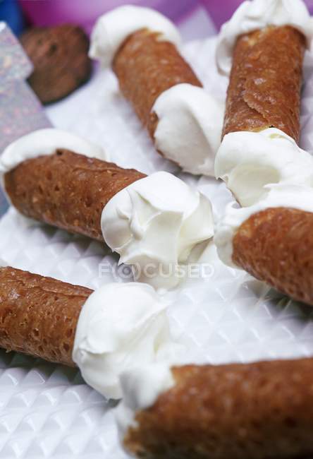 Closeup view of brandy snaps filled with cream on white plate — Stock Photo
