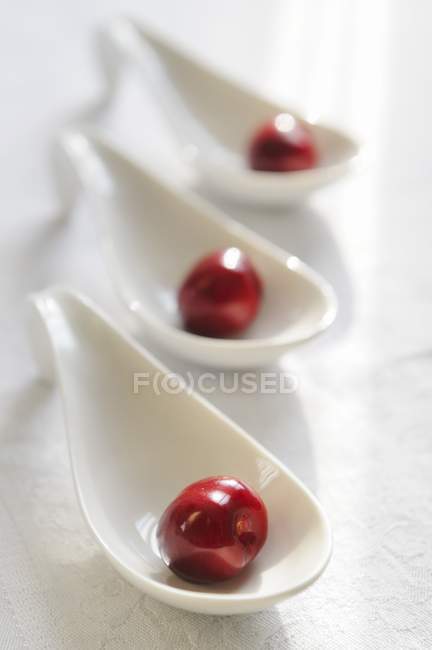 Cherries on porcelain spoons — Stock Photo