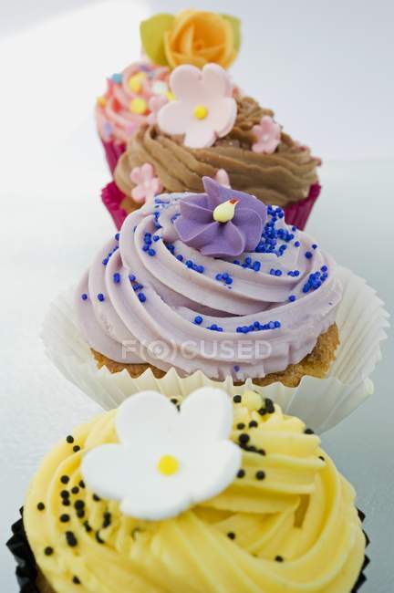 Reihe farbiger Cupcakes mit Blumen dekoriert — Stockfoto
