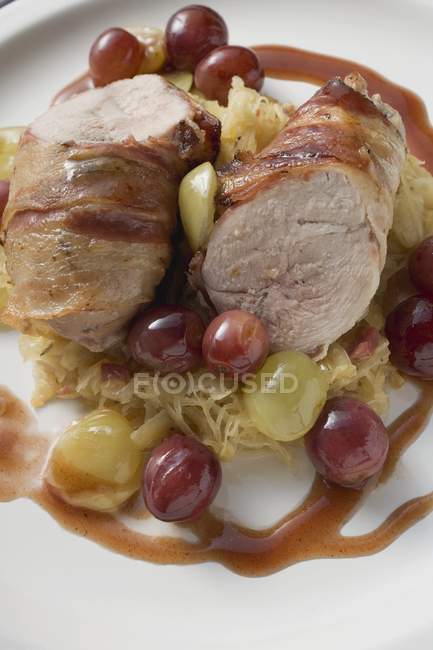 Pheasant breast with bacon, sauerkraut and grapes  on white plate — Stock Photo