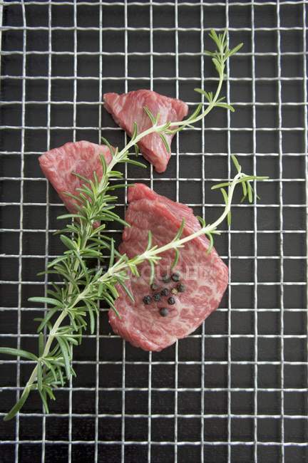 Trozos de carne Wagyu con romero y granos de pimienta - foto de stock