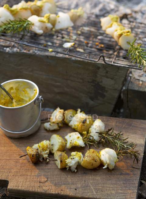 Gegrillter Fisch und Kartoffelspieße mit Curry auf Holztisch — Stockfoto