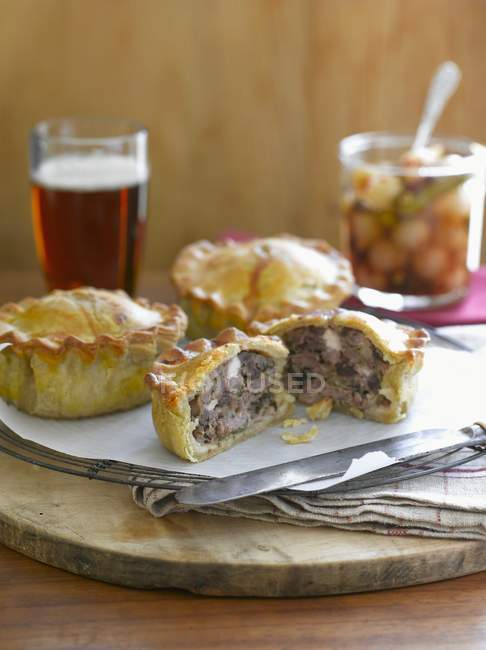 Closeup view of pies with pickles and a glass of beer — Stock Photo
