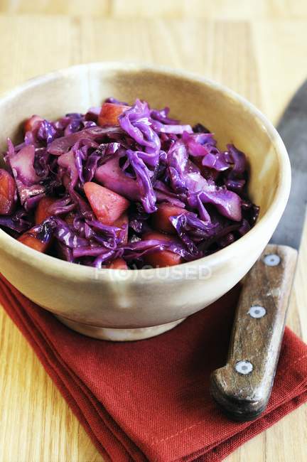 Apple red cabbage braised in red wine over red towel with knife — Stock Photo