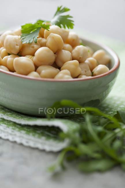 Chickpeas in a bowl with parsley over towel — Stock Photo
