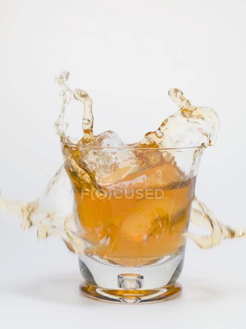 Cubo de hielo cayendo en un vaso de té - foto de stock