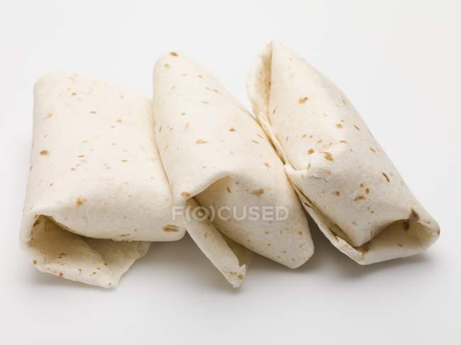 Closeup view of three Tortilla parcels on white surface — Stock Photo