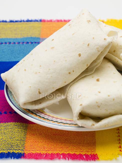 Primo piano vista di pacchi Tortilla sul piatto e panno colorato — Foto stock