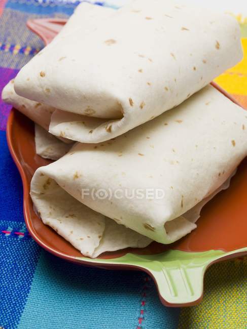 Closeup view of Tortilla parcels in dish on colored cloth — Stock Photo