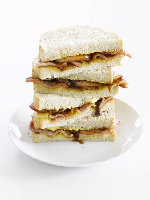 A stack of bacon and onion sandwiches  on white plate — Stock Photo