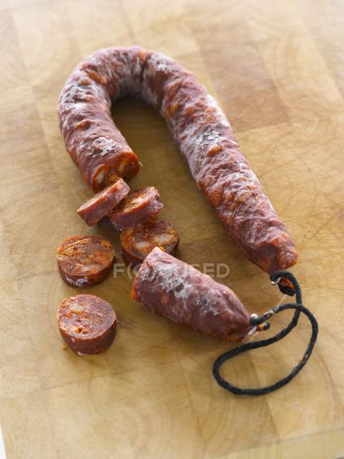 Elevated view of sliced Chorizo sausage on wooden surface — Stock Photo