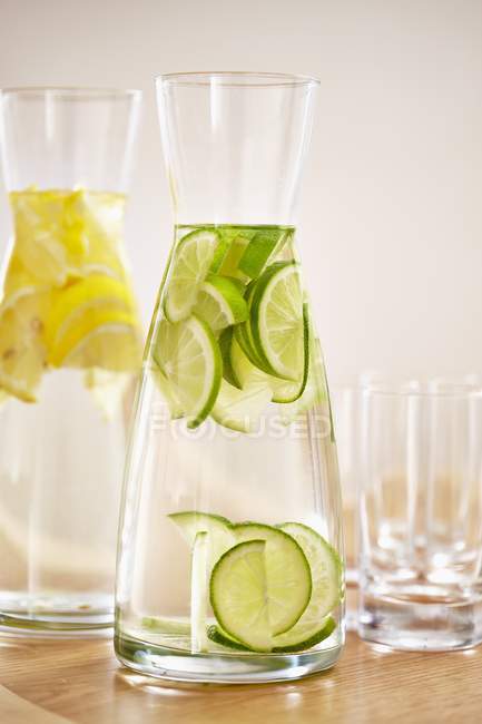 Nahaufnahme von Wasser mit Zitronen- und Limettenscheiben in Karaffen — Stockfoto