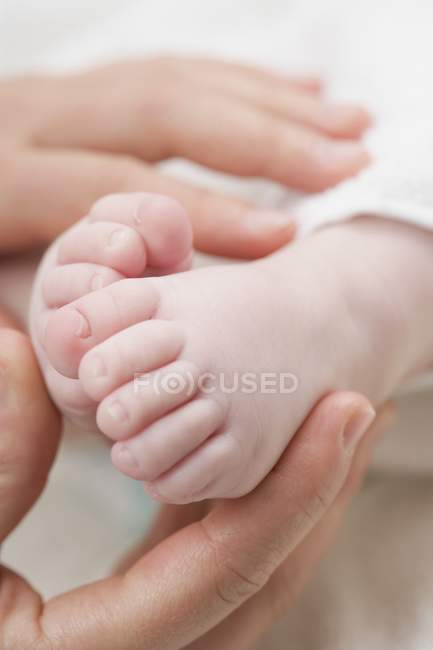 Primo piano vista delle mani che tengono i piedi del bambino — Foto stock