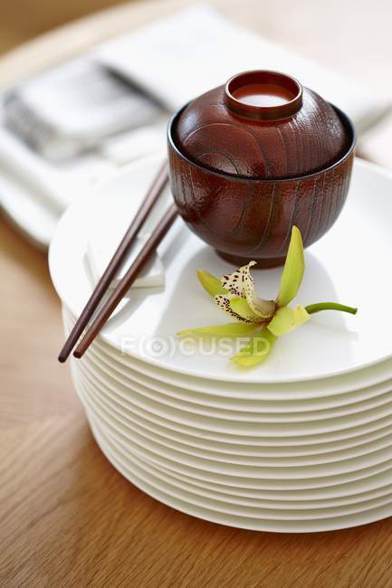 Une fleur d'orchidée et un bol verni sur une pile de plaques — Photo de stock