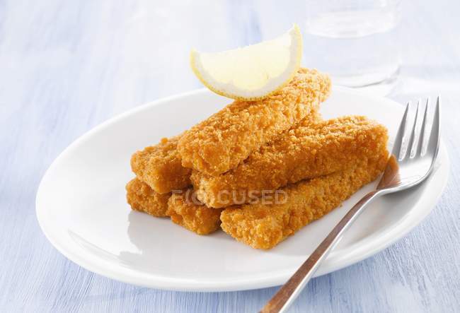 Breaded fish fingers with lemon wedge — Stock Photo