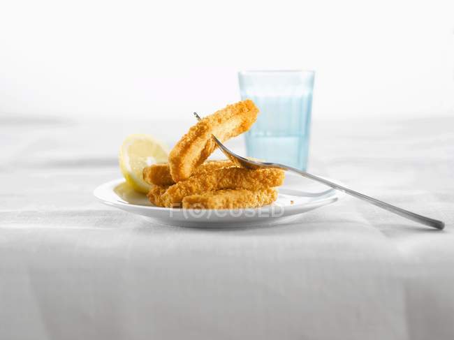 Fischstäbchen mit Zitrone auf Teller — Stockfoto