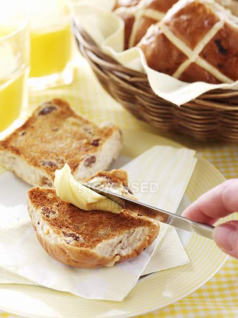 Vue rapprochée d'une main écartant un pain croisé chaud avec du beurre — Photo de stock