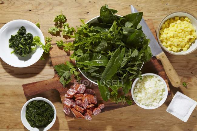 Ingredientes para Heggenms guisado feito com ervas silvestres, couve verde e salsichas sobre a superfície de madeira — Fotografia de Stock