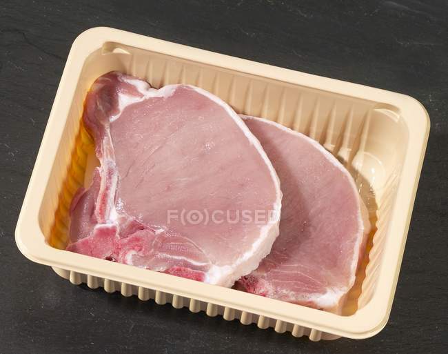 Raw pork chops in plastic container — Stock Photo