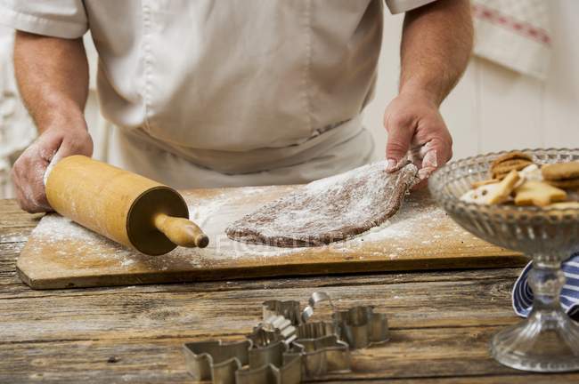 Cropped view of a confectioner holding a rolling pin and biscuit dough — Stock Photo