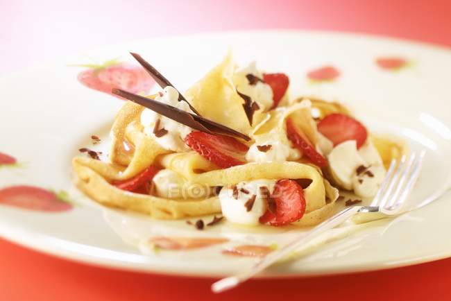 Closeup view of crepes with strawberries, cream and chocolate shavings — Stock Photo